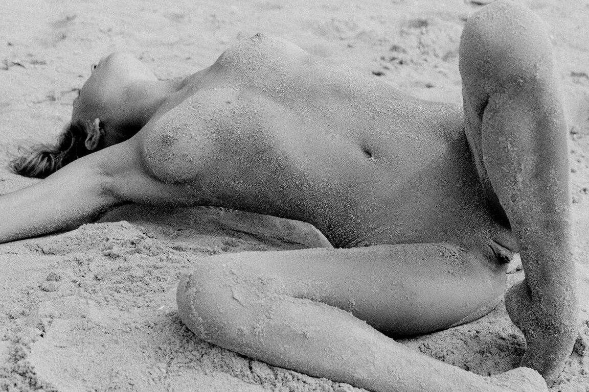 21P Barefoot babe with a skinny body Olga rubs her twat while rolling in the sand