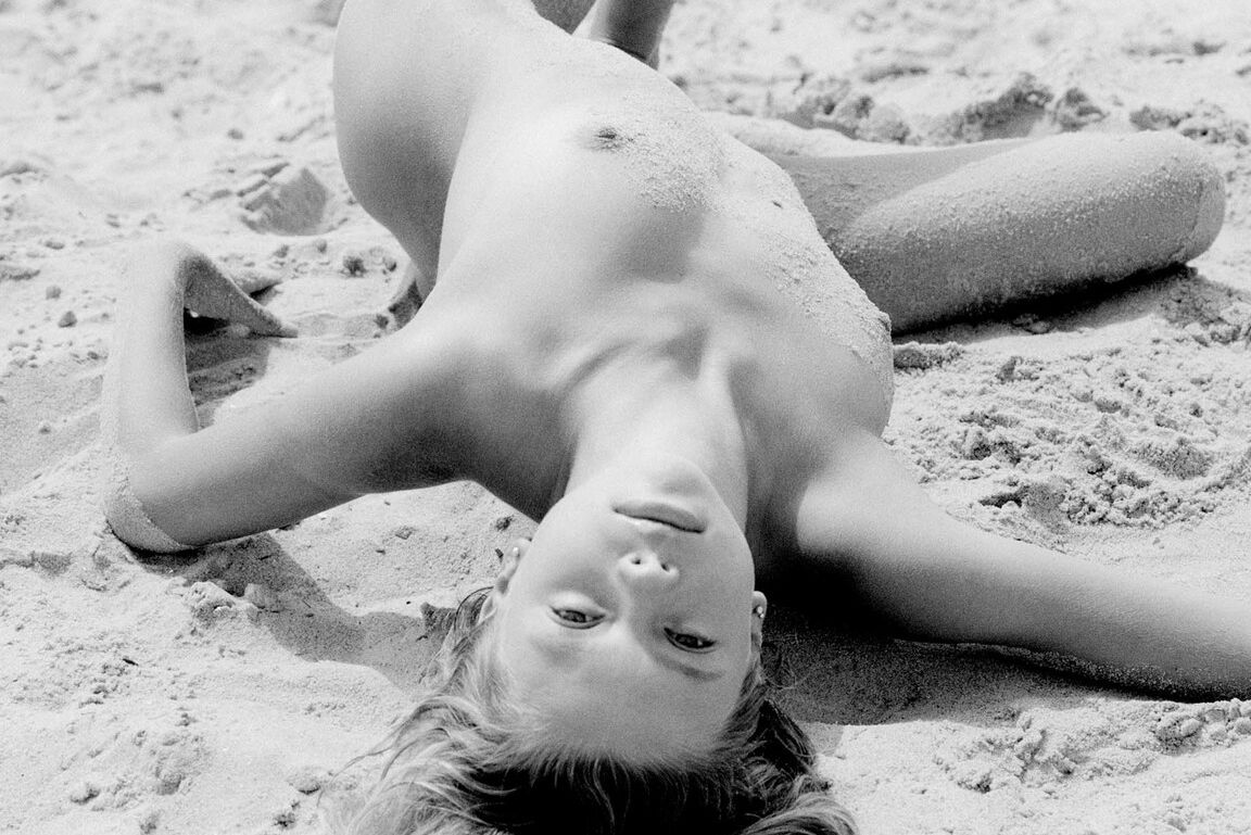 21P Barefoot babe with a skinny body Olga rubs her twat while rolling in the sand