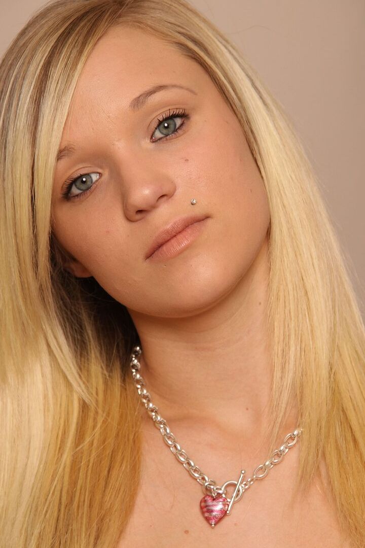 16P La joven rubia Teagan descubre sus pequeñas tetas mientras se desnuda en un sofá