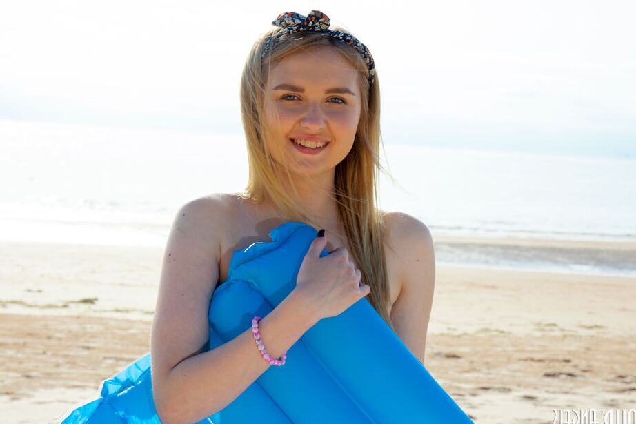 20P Die junge blonde Nimfa zieht am Strand ihre Shorts aus, um sich nackt in der Sonne auszubreiten