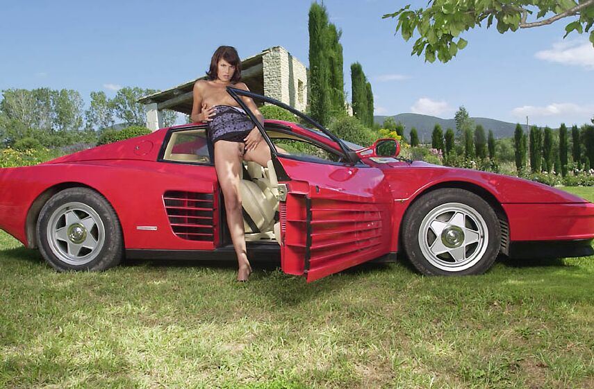 21P A deslumbrante MILF húngara Jade Wolf fica nua e posa em um carro vermelho ao ar livre
