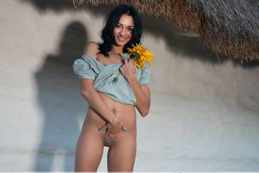 16P Dark haired teen Valeria E holds a sunflower while naked behind a building