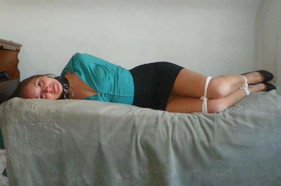 16P Collared woman is tied up on a bed in a black miniskirt and pumps