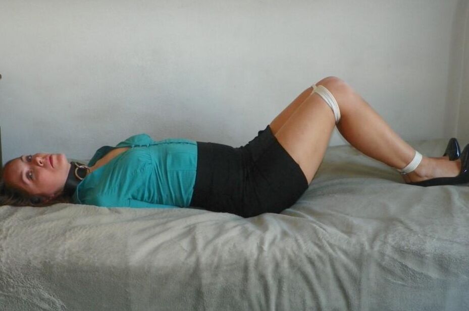 16P Collared woman is tied up on a bed in a black miniskirt and pumps