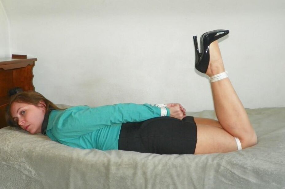 16P Collared woman is tied up on a bed in a black miniskirt and pumps