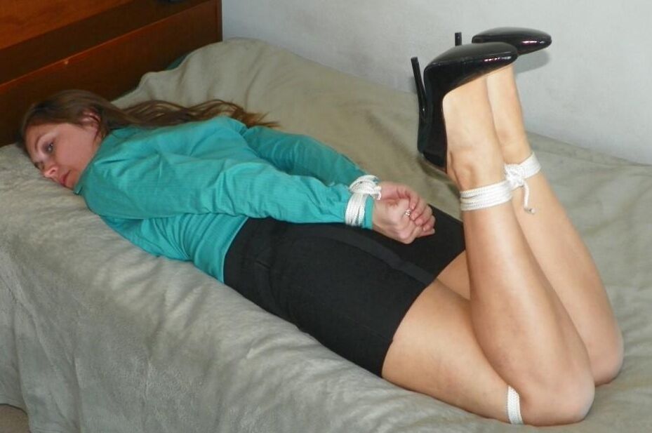 16P Collared woman is tied up on a bed in a black miniskirt and pumps
