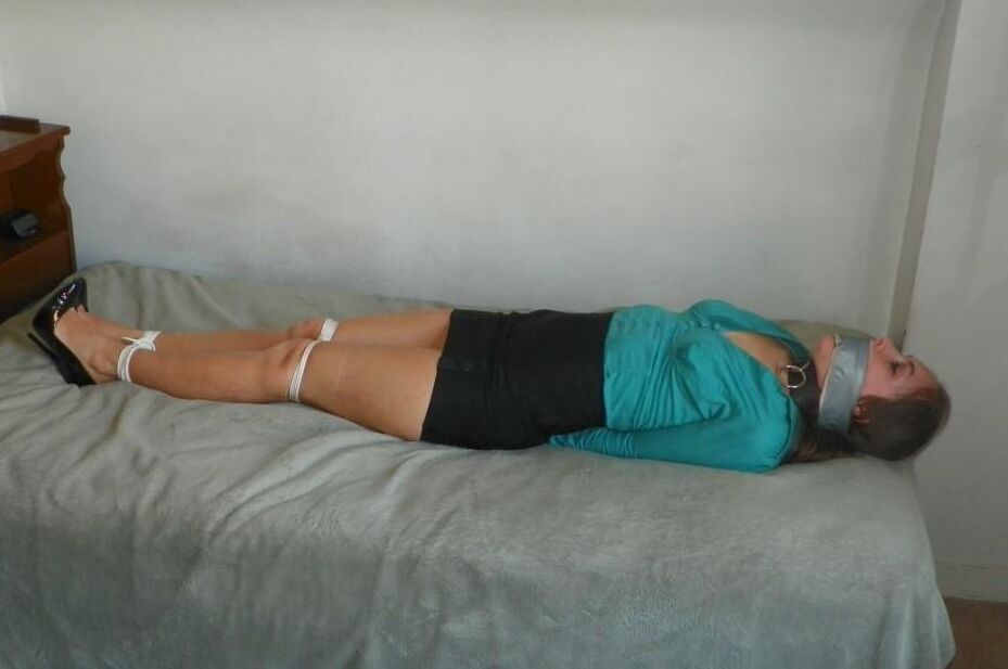 16P Collared woman is tied up on a bed in a black miniskirt and pumps