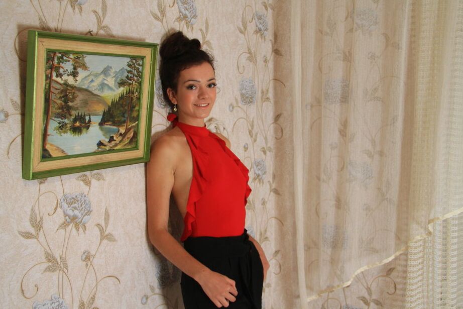 16P La mannequin adolescente Victoria F porte ses cheveux relevés tout en se déshabillant sur son lit.