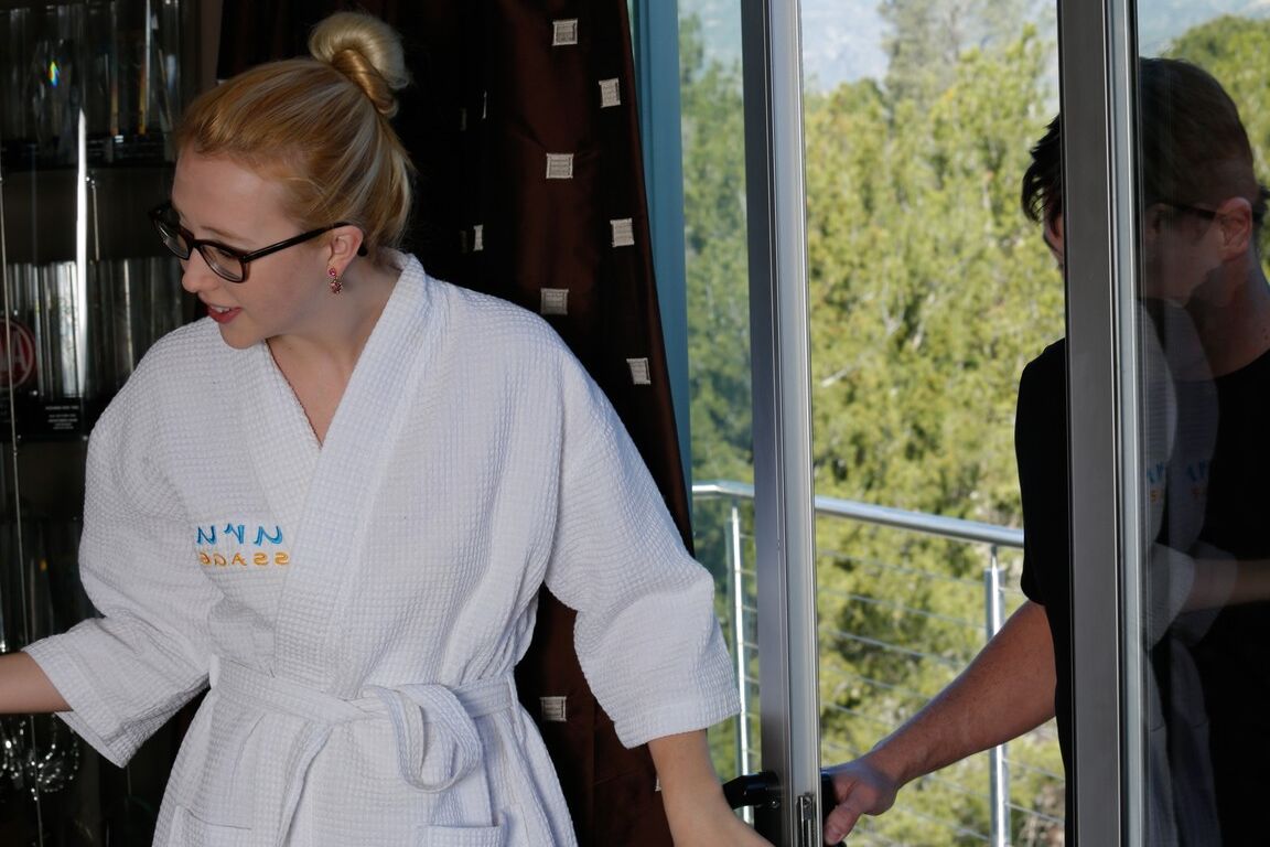 17P A massagista loira de óculos, Samantha Rone, dá as boas-vindas ao seu cliente com um roupão