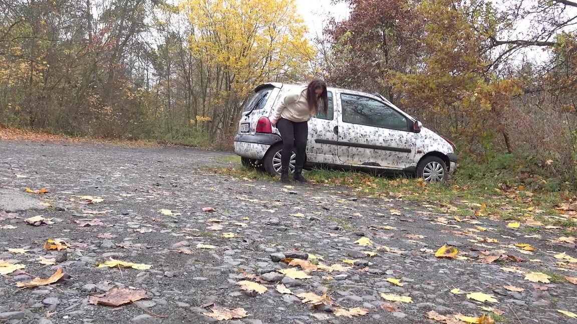 15P White girl Nicolette Noir takes a piss beside a parked car in a wooded setting