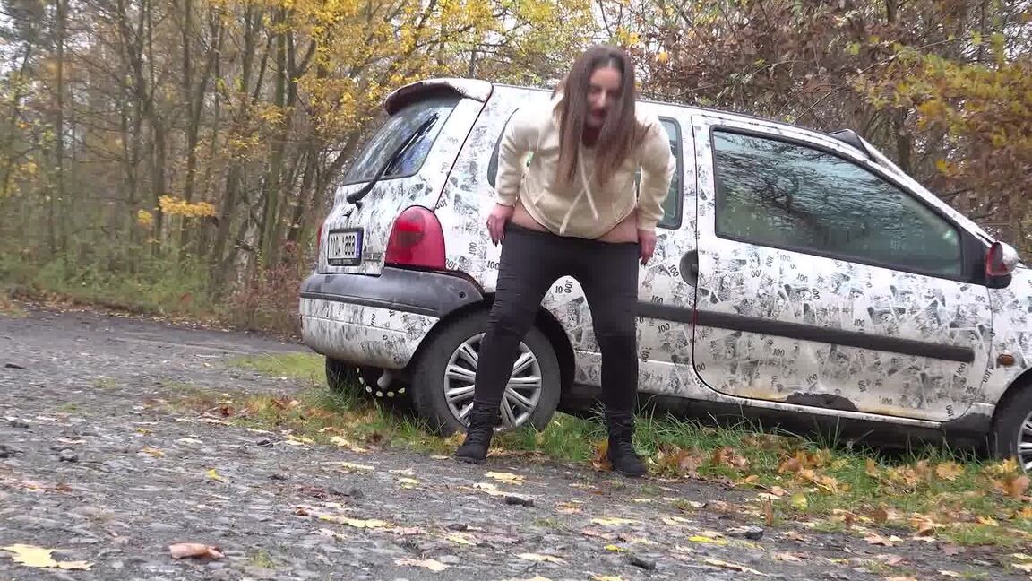 15P White girl Nicolette Noir takes a piss beside a parked car in a wooded setting