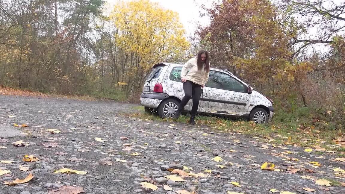 15P White girl Nicolette Noir takes a piss beside a parked car in a wooded setting