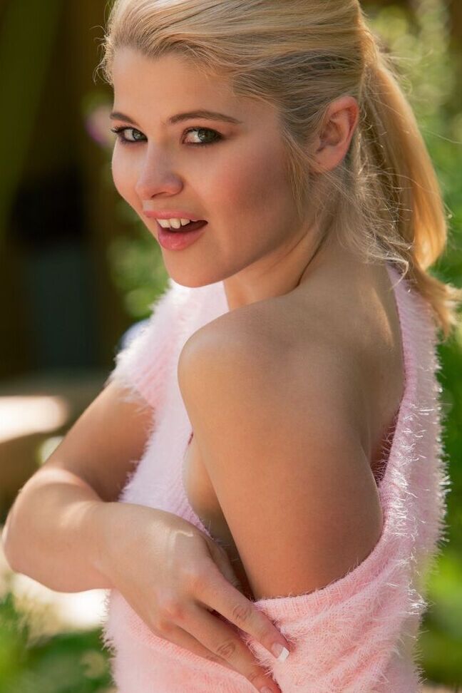 15P Young blonde Mindy Corin holds a flower after getting naked in a garden