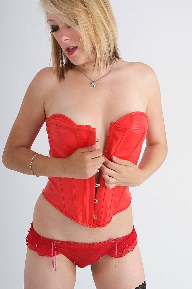 15P Die sexy Blondine Jay lässt ihre natürlichen Titten aus einem roten Lederkorsett in Strümpfen fallen