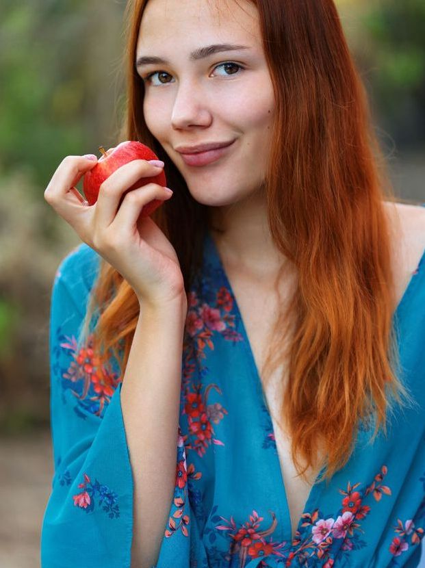 18P Beautiful red haired Janey takes a bite of an apple, divests her clothing and