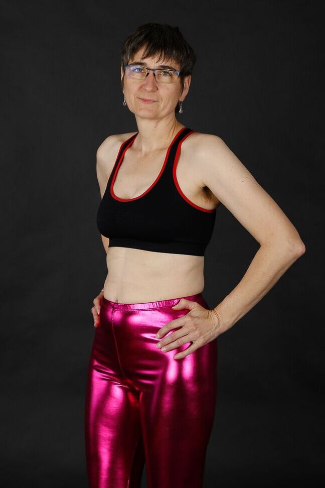 20P Femme mature modèle un soutien-gorge de sport dans un pantalon brillant et des bottes noires