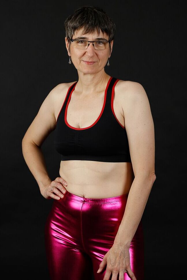 20P Femme mature modèle un soutien-gorge de sport dans un pantalon brillant et des bottes noires