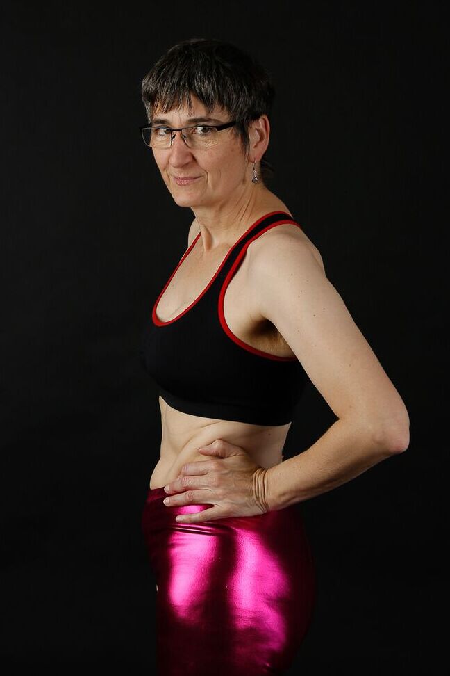 20P Femme mature modèle un soutien-gorge de sport dans un pantalon brillant et des bottes noires