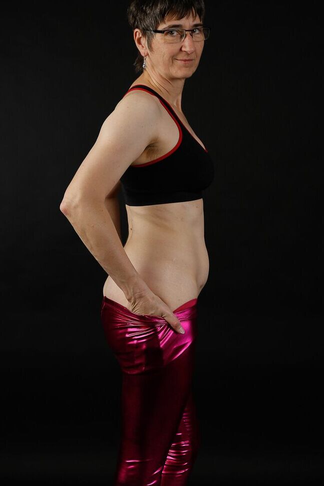 20P Femme mature modèle un soutien-gorge de sport dans un pantalon brillant et des bottes noires