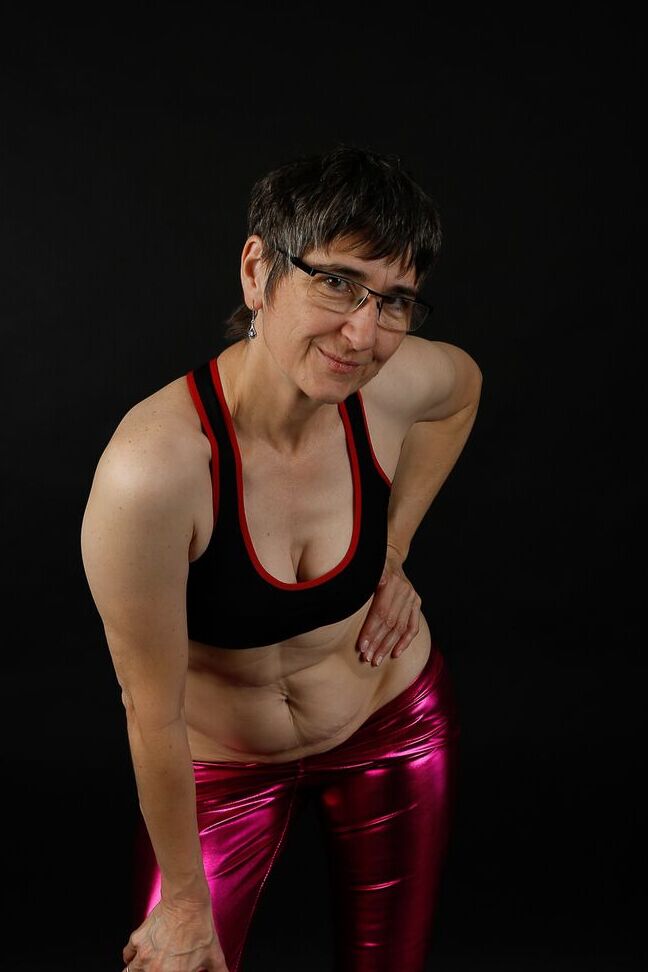20P Femme mature modèle un soutien-gorge de sport dans un pantalon brillant et des bottes noires
