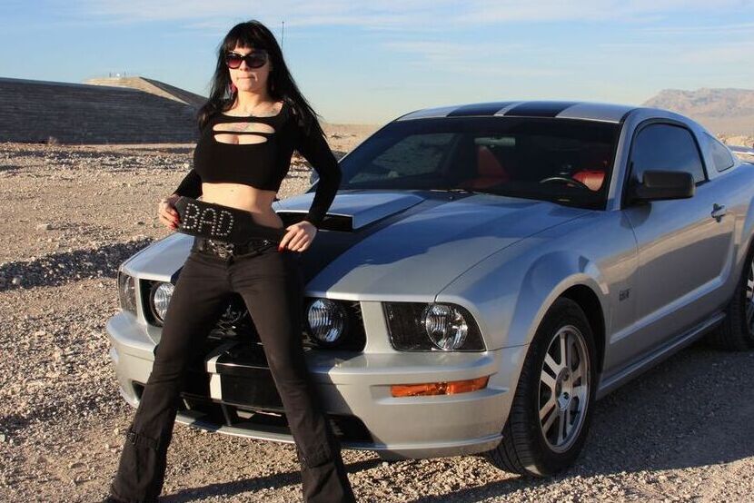 20P A garota sexy Susy Rocks expõe o sutiã sobre o capô de um carro em óculos escuros
