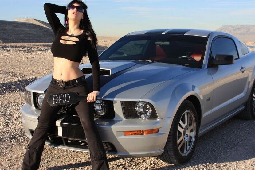 20P A garota sexy Susy Rocks expõe o sutiã sobre o capô de um carro em óculos escuros