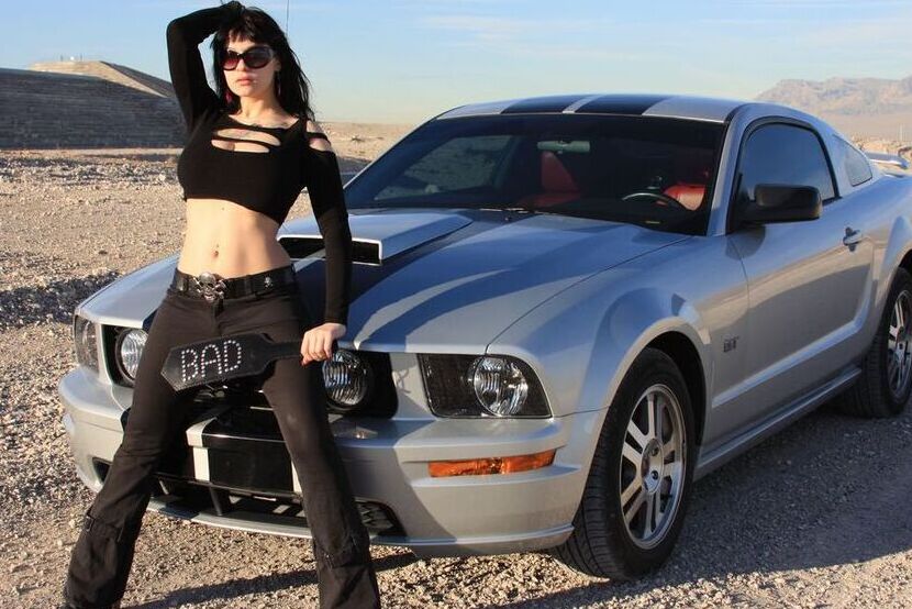 20P A garota sexy Susy Rocks expõe o sutiã sobre o capô de um carro em óculos escuros