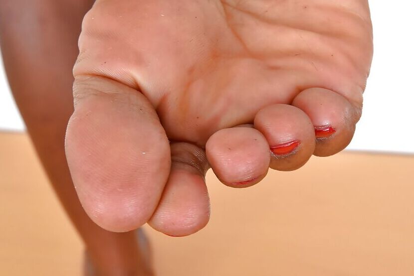 16P Mulher negra mais velha exibindo pernas sensuais e unhas pintadas