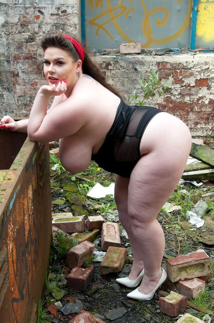 15P Brunette fatty Gina G unleashes her knockers while getting naked near graffiti