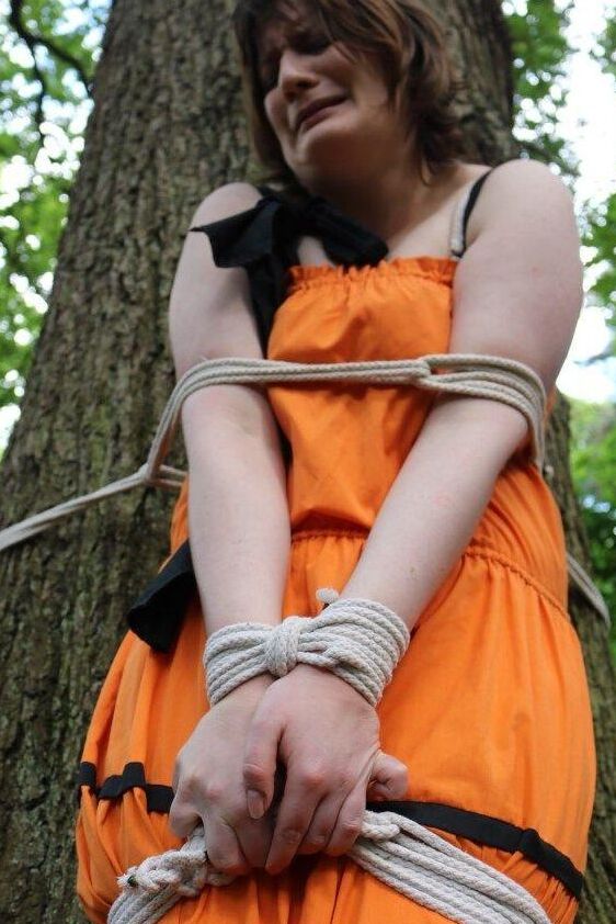 16P 太った女性が猿轡をされ、服を着たまま森の木に縛り付けられる