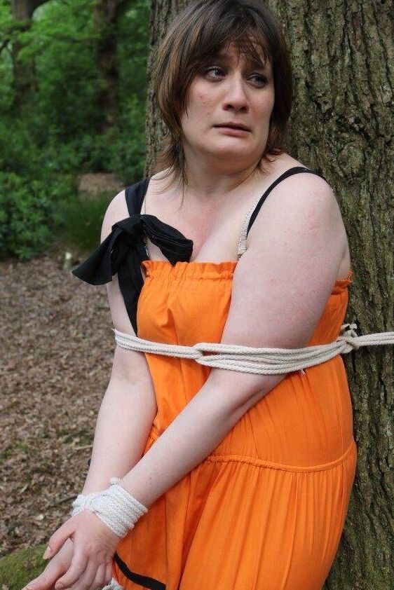 16P 太った女性が猿轡をされ、服を着たまま森の木に縛り付けられる