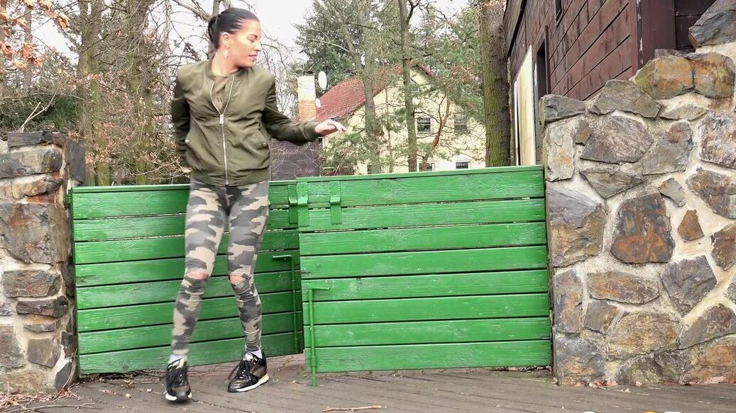 15P Brunette chick Dellai pulls down camo pants for a badly needed pee in public
