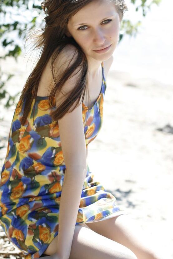 16P, Lilly B, une fille caucasienne, montre ses petits seins et sa chatte sur une plage de sable.