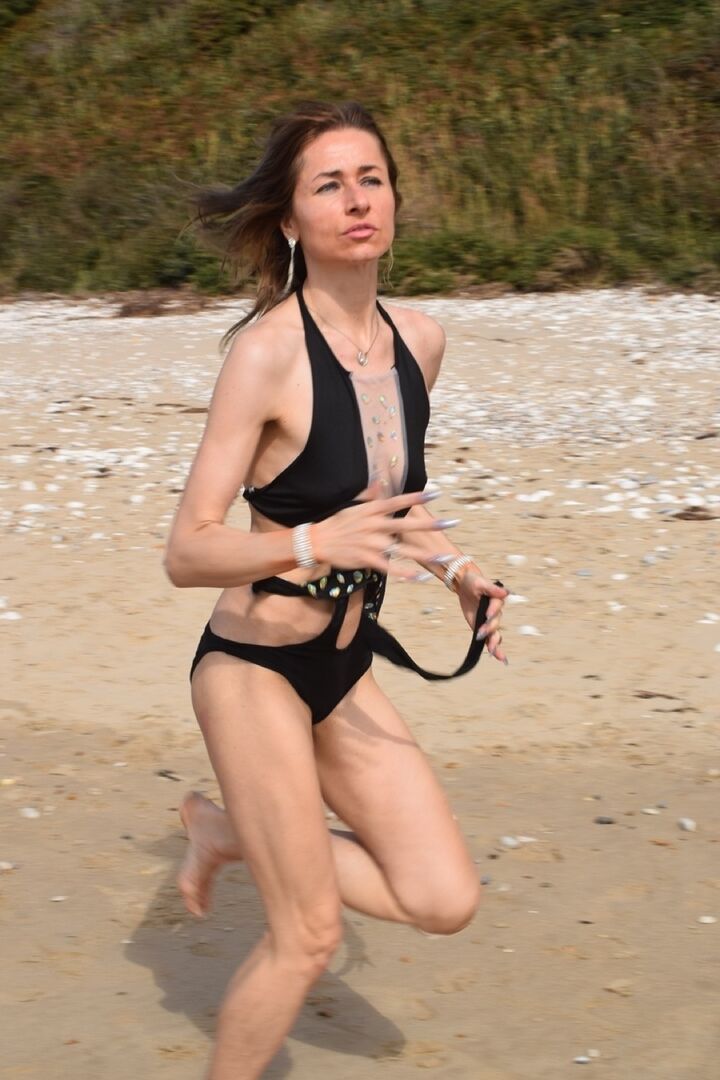 16P Schlanke Frau modelliert einen Badeanzug an einem einsamen Strand