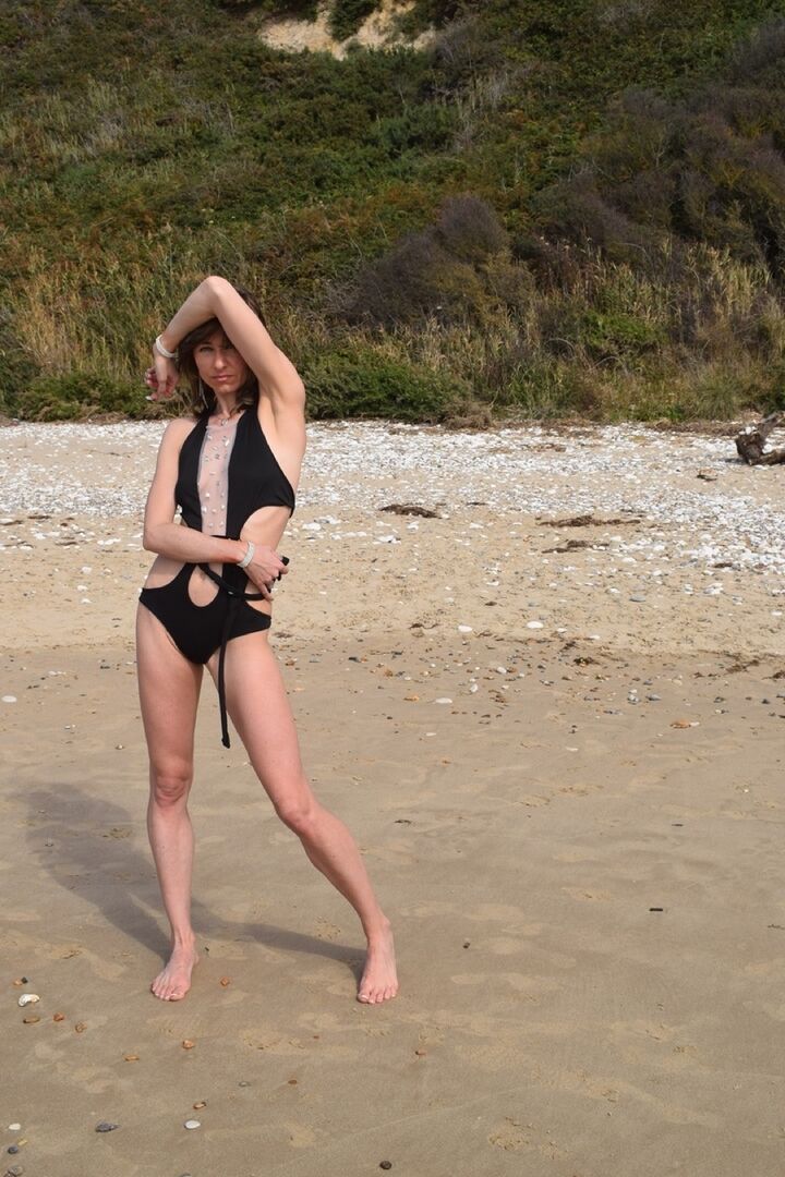 16P Schlanke Frau modelliert einen Badeanzug an einem einsamen Strand