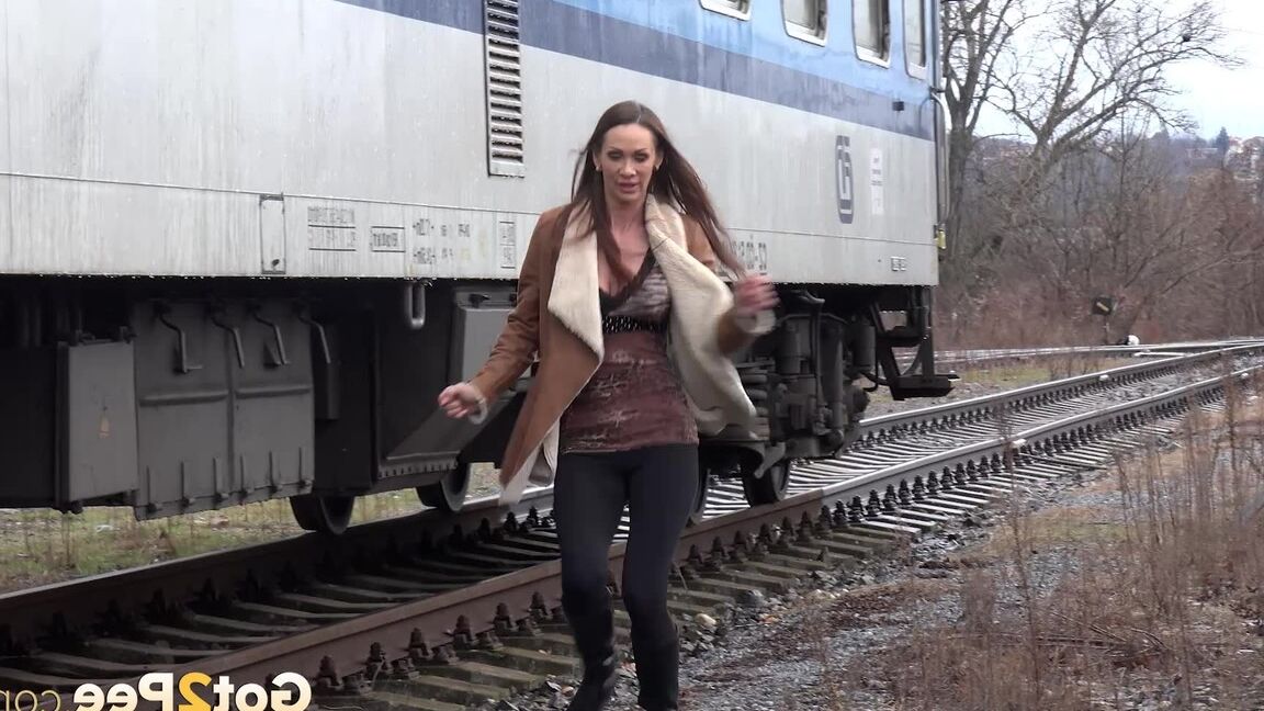 15P Cynthia Vellons pulls down black tights for a quick piss near railway cars