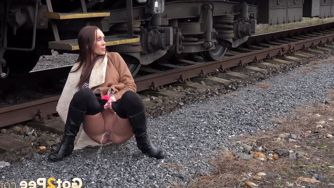 15P Cynthia Vellons pulls down black tights for a quick piss near railway cars