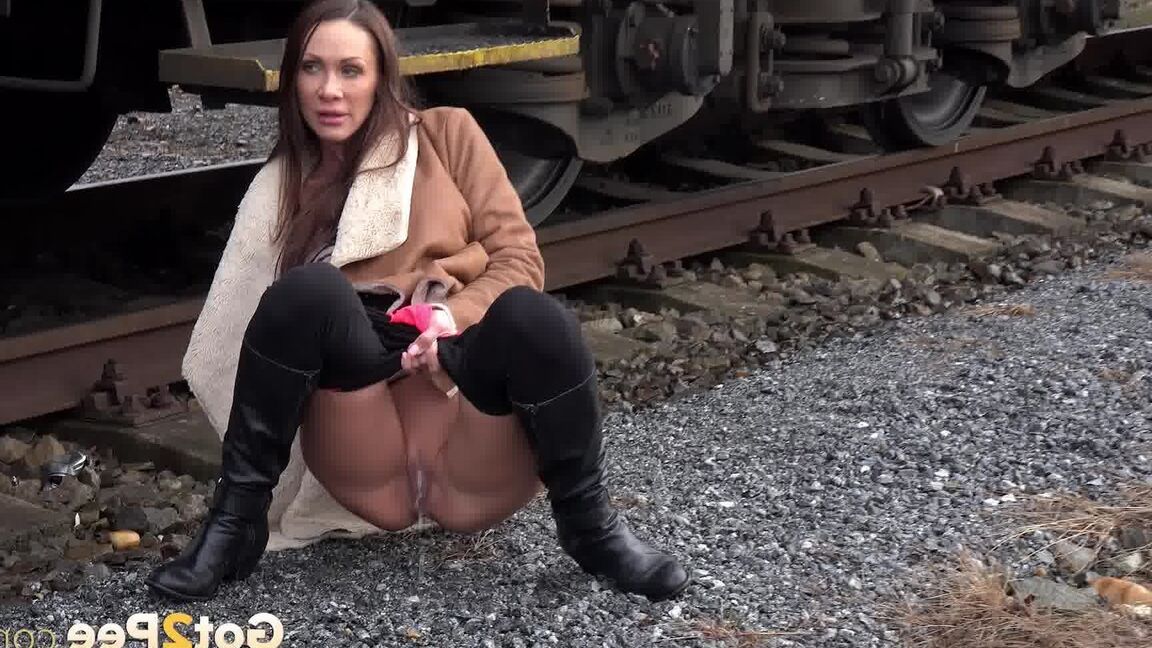 15P Cynthia Vellons pulls down black tights for a quick piss near railway cars