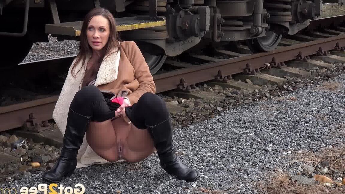 15P Cynthia Vellons pulls down black tights for a quick piss near railway cars