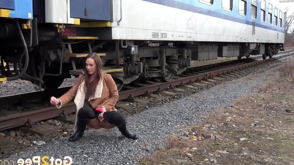 15P Cynthia Vellons pulls down black tights for a quick piss near railway cars