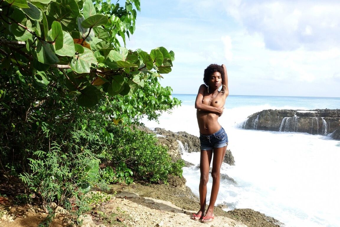 16P In front of the waves crashing on the rocks, a beautiful young black girl is