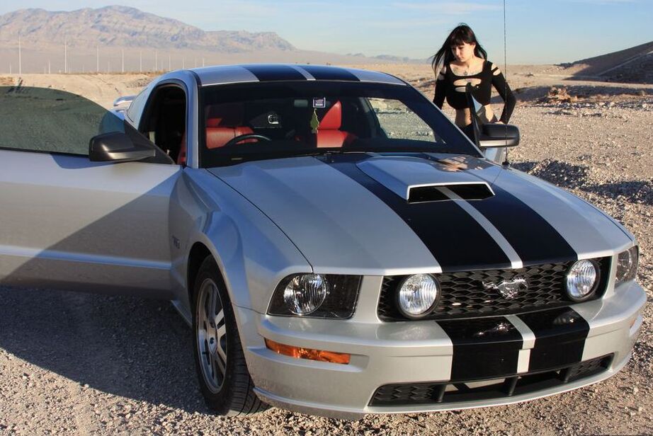 20P Brunette amateur Susy Rocks models by a muscle car during a safe for work gig
