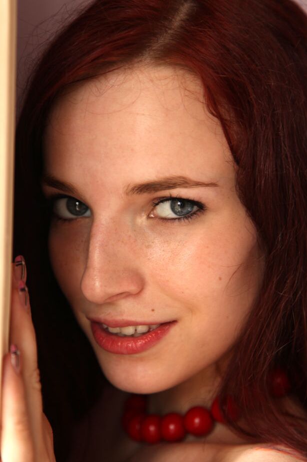 18P Young redhead Leila Smith drapes herself in a feather boa while modeling naked