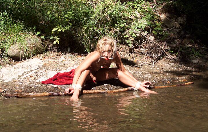 12P Chica rubia atada de manos y muñecas después de ser amordazada con una pelota a la orilla del río