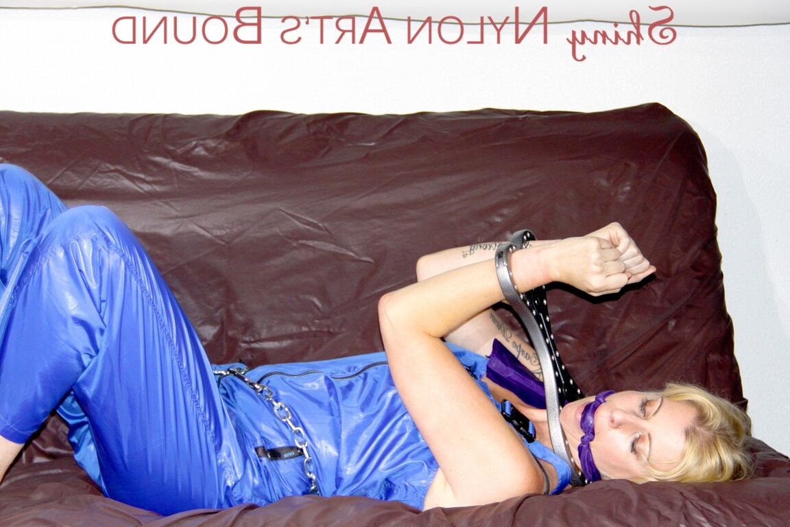 16P PIA tied and gagged with a pillory on a sofa wearing a sexy blue really shiny