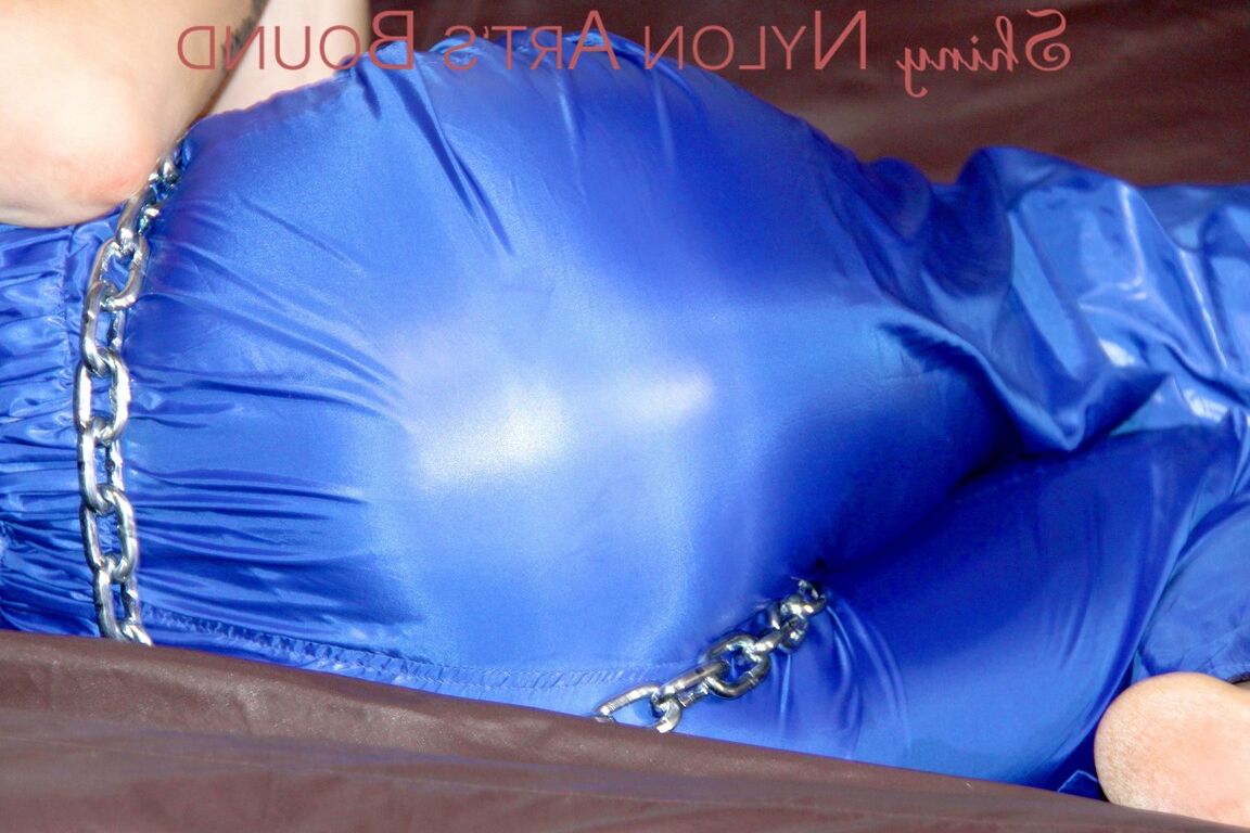 16P PIA tied and gagged with a pillory on a sofa wearing a sexy blue really shiny