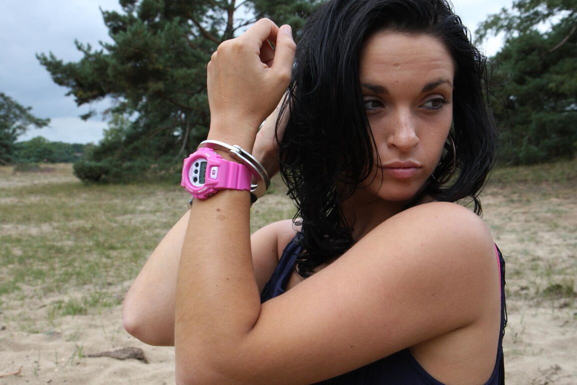 16P Брюнетка Нора прикована наручниками к дереву и носит розовые часы G-Shock.
