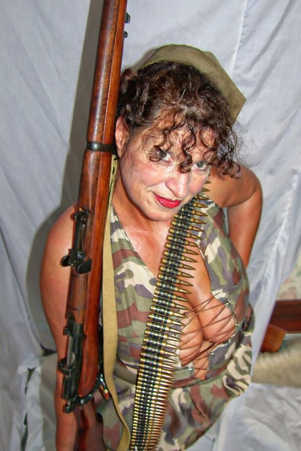 20P Une femme mûre en surpoids expose ses jarretelles et ses hauts en nylon dans des vêtements militaires