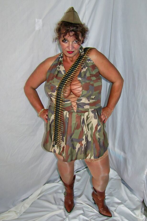 20P Une femme mûre en surpoids expose ses jarretelles et ses hauts en nylon dans des vêtements militaires
