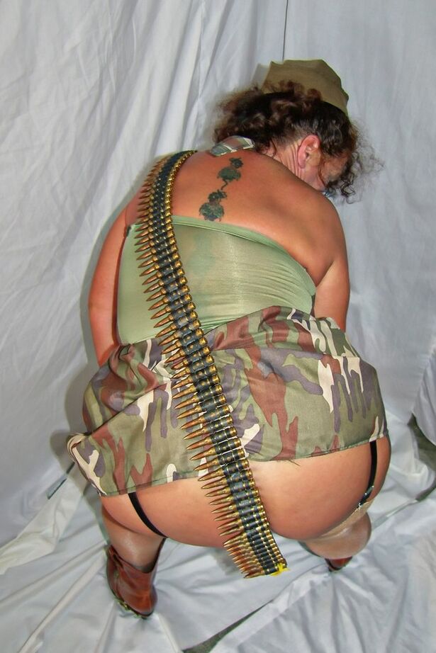 20P Une femme mûre en surpoids expose ses jarretelles et ses hauts en nylon dans des vêtements militaires